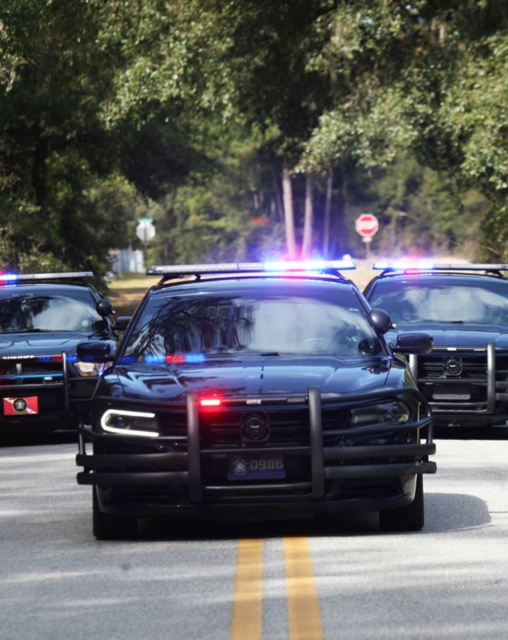 3 police cars with red and blue lights on 